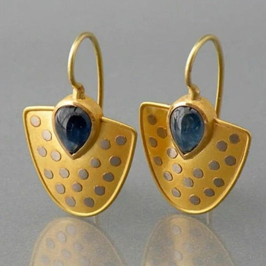 Elegantes goldenes Schild mit funkelnden blauen Kristall-Ohrringen