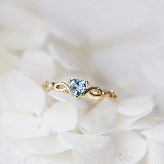 Eleganter herzförmiger Ring aus Gold mit funkelnden blauen Zirkonia-Steinen