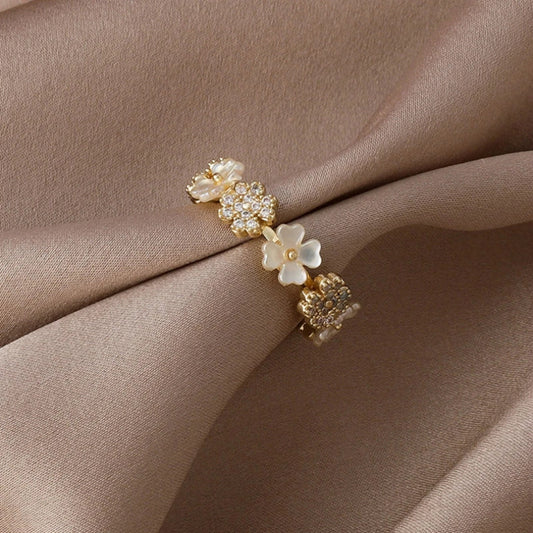 Eleganter verstellbarer Goldring mit weißen Blumen und funkelnden Zirkoniasteinchen