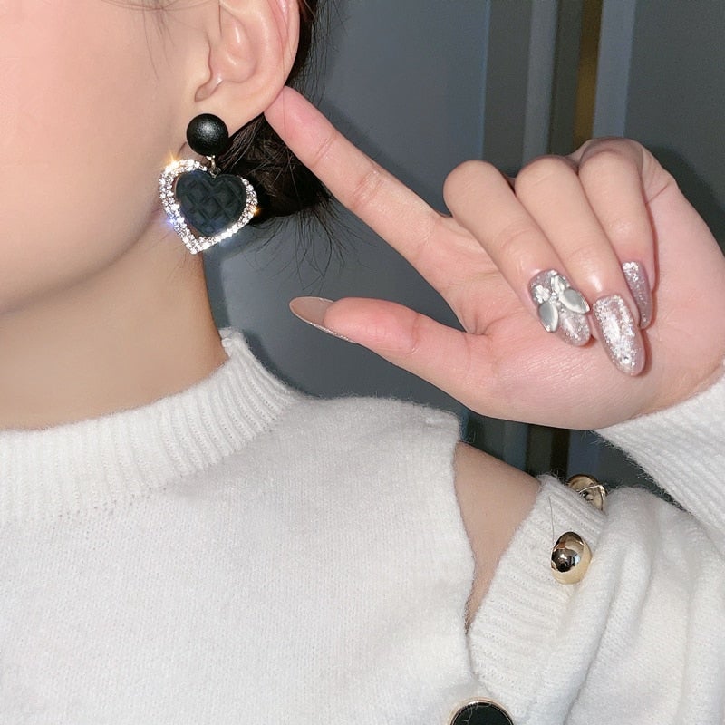 Elegante goldene Ohrringe mit dunklem Herzdesign