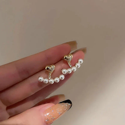 Elegante goldene Ohrringe mit Perlenherzen