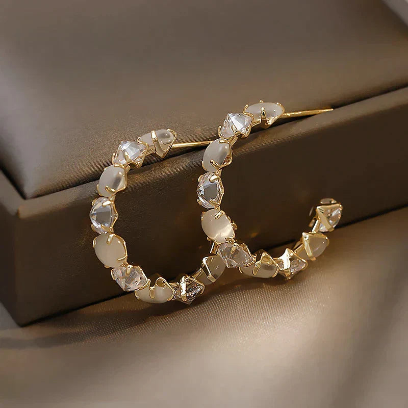 Elegante goldene Ohrringe mit weißen Opalen und funkelnden Zirkonia-Steinen
